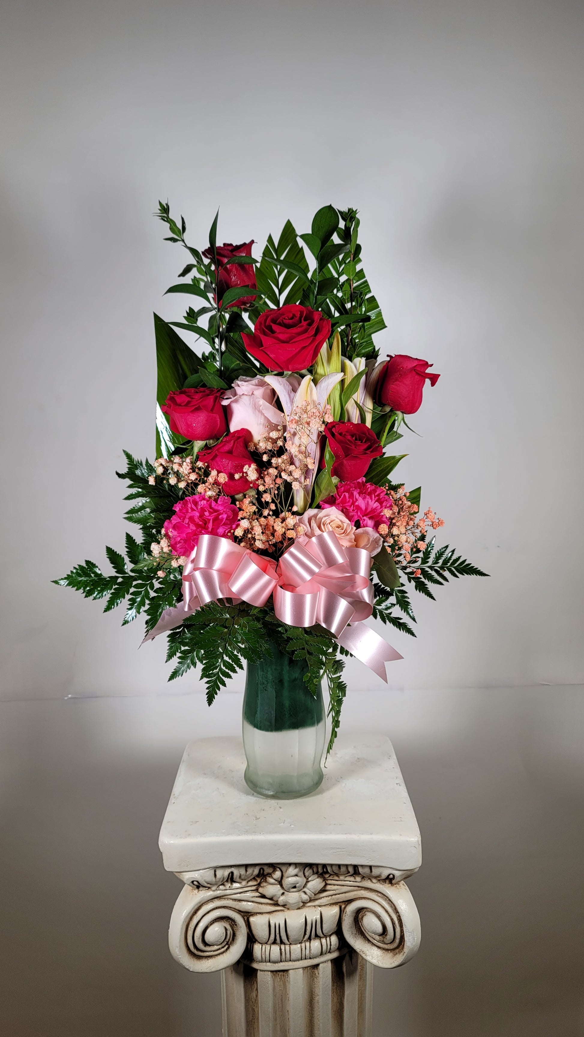 Pink and red rose bouquet in glass vase with lilies carnations and ribbon in Houston