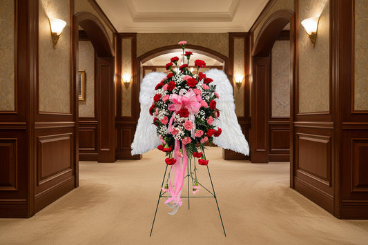 Pink and red standing sympathy spray with angel wings baby breath and greenery in Houston