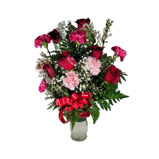 Red and pink rose vase arrangement with carnations baby breath greenery and ribbon by Houston florist