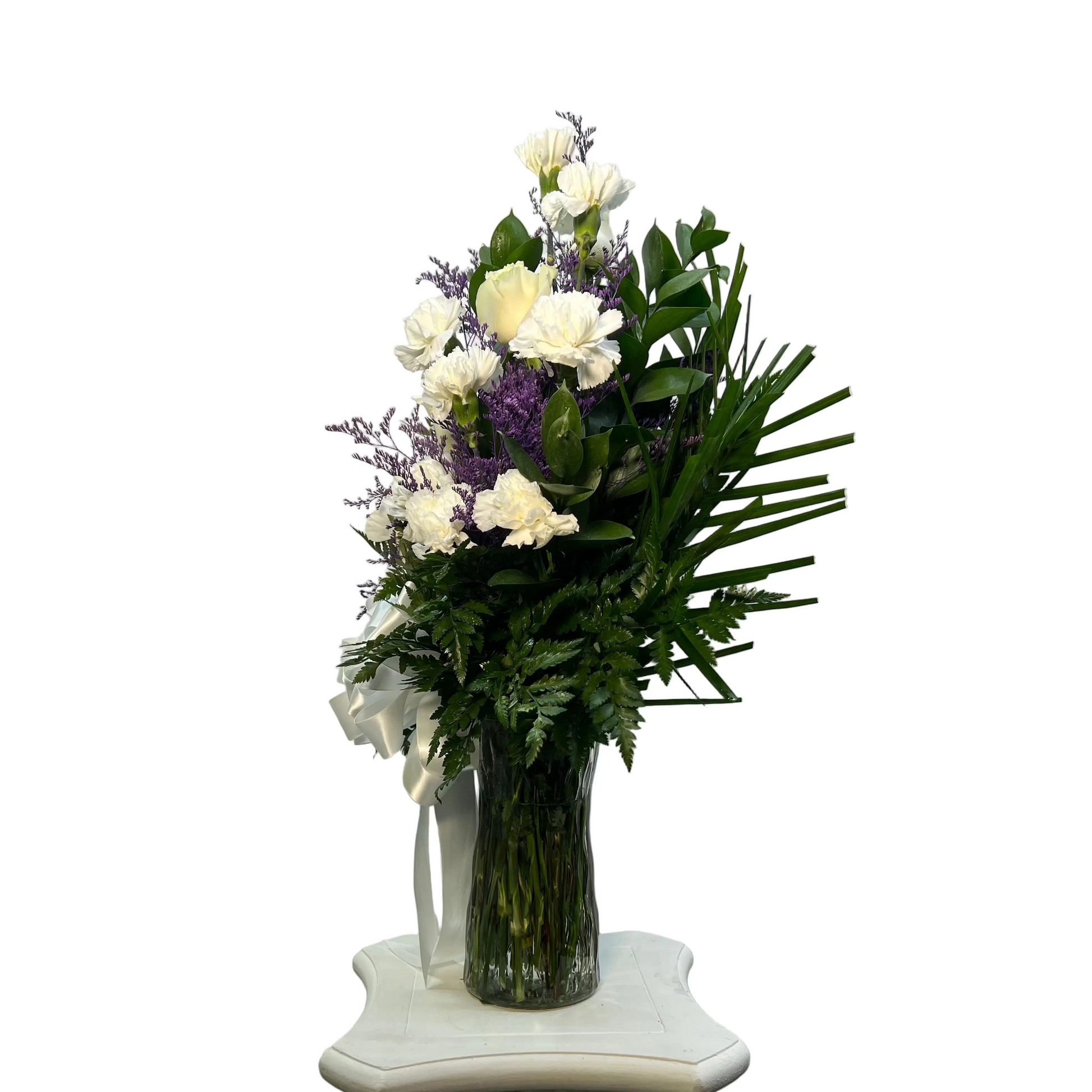 Bouquet of flowers in a clear vase on a decorative pedestal against a plain background